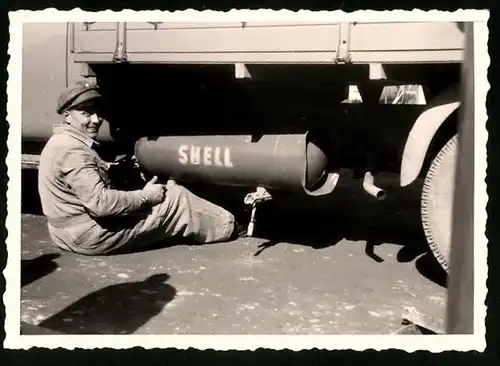 Fotografie Lastwagen, Mechaniker demontiert verbeulten Druckluftbehälter (mit Aufschrift Shell) der Bremsanlage