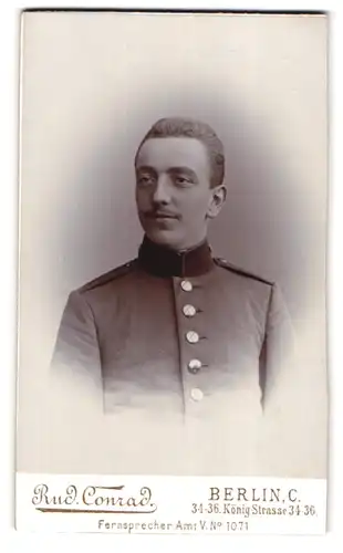 Fotografie Rud. Conrad, Berlin, Königstrasse 34-36, Soldat in Uniform mit zurück gewachstem Haar
