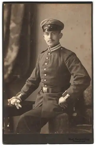 Fotografie Rud. Lichtenberg, Osnabrück, Soldat mit Schirmmütze und Uniform hält Handschuhe