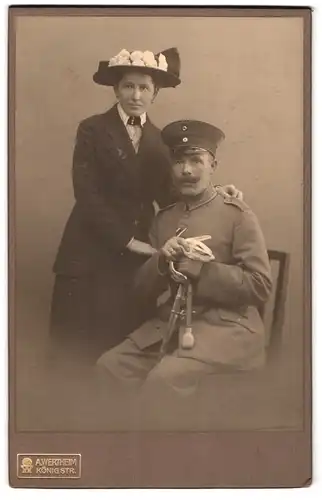 Fotografie A. Wertheim, Berlin, König Str., Sitzender Soldat in Uniform mit Säbel und Frau