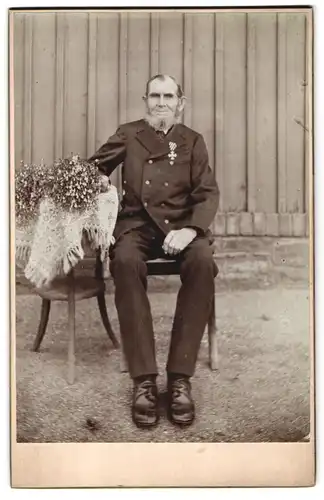 Fotografie unbekannter Fotograf und Ort, Sitzender Veteran mit Orden