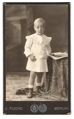 Fotografie J. Fuchs, Berlin-N., Friedrichstr. 108, Kleiner Junge im Kleid mit einem Heft