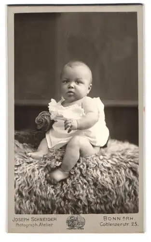 Fotografie Joseph Schneider, Bonn a. Rh., Coblenzerstr. 25, Süsses Kleinkind im Hemd sitzt auf Fell