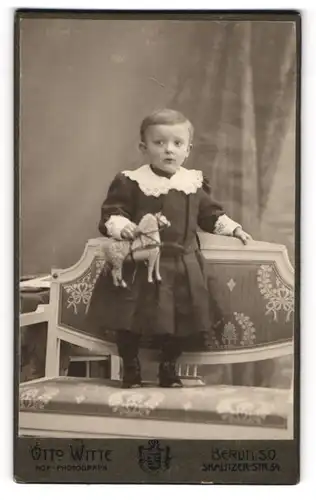 Fotografie Otto Witte, Berlin, Skalitzerstr. 54, kleiner Knabe im Kleid mit Spielzeugpferd in der Hand