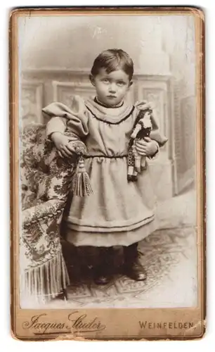 Fotografie Jaques Studer, Weinfelden, kleines Mädchen mit ihrer Puppe im Arm schaut skeptisch