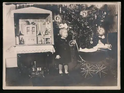 Fotografie Weihnachten, Mädchen mit Puppe, Puppenwagen, Kinderherd & Puppenstube neben dem Weihnachtsbaum