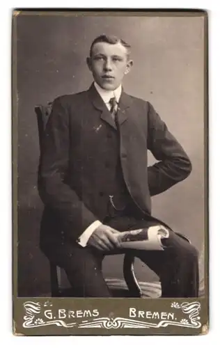 Fotografie G. Brems, Bremen, Landwehrstr. 40, Portrait junger Mann elegant im Anzug mit Zeitschrift in der Hand