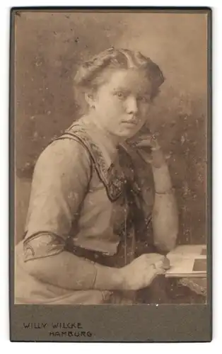 Fotografie Willy Wilcke, Hamburg, Steindamm 54 /56, Portrait hübsches Fräulein mit Buch auf dem Tisch liegend