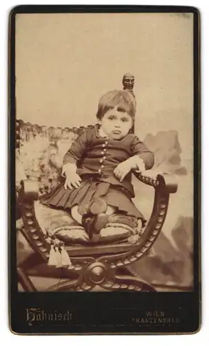 Fotografie H. Hähnisch, Wien, Mayerhofgasse 11, Skeptisch schauendes kleines Mädchen auf Sitzmöbel