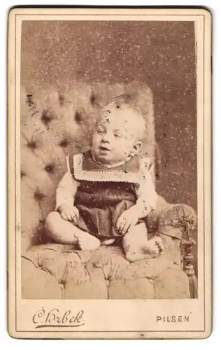 Fotografie C. Hrbeck, Pilsen, Baby im Kleidchen auf Sitzmöbel