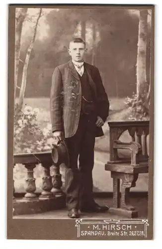 Fotografie M. Hirsch, Spandau, Breite Strasse 26, Junger Mann mit Uhrenkette und Hut in der Hand