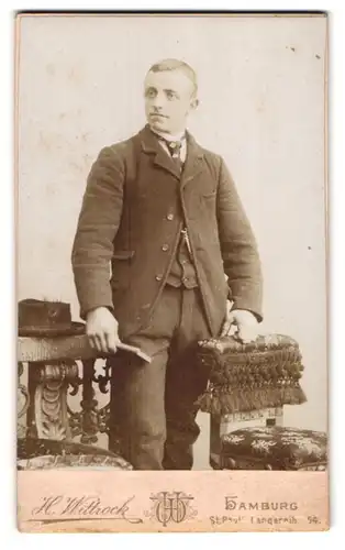 Fotografie H. Wittstock, Hamburg, Langereihe 54, eleganter junger Mann im Anzug neben Stühlen