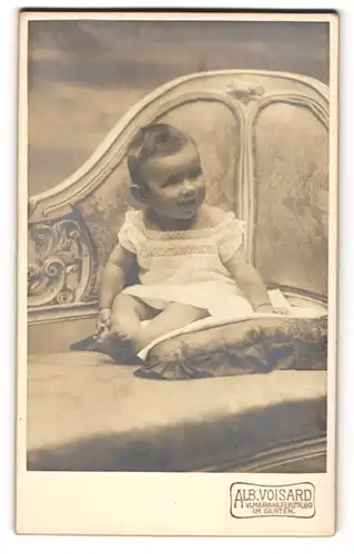 Fotografie Alb. Voisard, Wien, Mariahilferstr. 89, Süsses Kleinkind im weissen Hemd mit nackigen Füssen