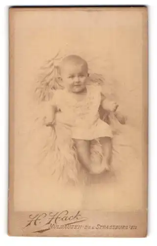 Fotografie H. Hack, Mülhausen /Els., Ecke Alt St. Peter Platz, Lächlndes Baby auf Fell