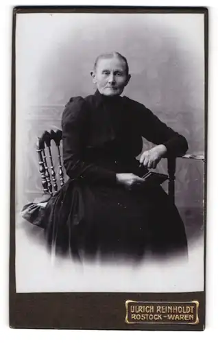 Fotografie Ulrich Reinholdt, Rostock, Kröpeliner Strasse 40, Gestandene Frau im schwarzen Kleid mit Buch in der Hand