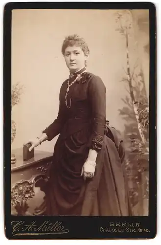 Fotografie C. A. Müller, Berlin, Chaussee-Strasse 40, Junge Dame mit Arm- und Halsschmuck in tailliertem Kleid