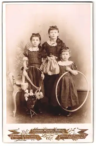Fotografie Theodor Wenzel, Berlin O., Andreasstrasse 28, Drei Mädchen mit Blumenkorb, Puppe und Reifen