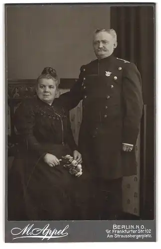 Fotografie M. Appel, Berlin, Gr. Frankfurter Str. 102, Portrait Eisenbahner in Uniform mit Abzeichen nebst seiner Frau