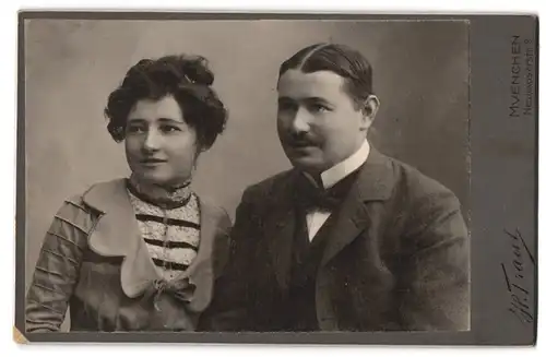 Fotografie H. Traut, München, Neuhauserstrasse 9, Lächelndes junges Paar in sonntäglicher Kleidung
