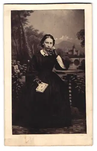 Fotografie Carl Huberti, Traunstein, Portrait junge Dame im dunklen Biedermeierkleid posiert vor einer Studiokulisse