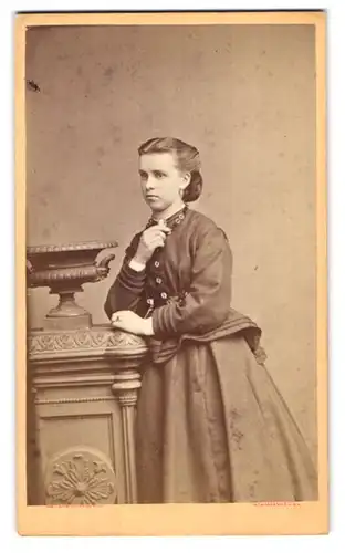 Fotografie H. Mathaus, München, Schwanthalerstr. 10, junge Frau im Biedermeierkleid mit Brosche in der Hand