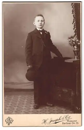 Fotografie H. Joseph & Co., Rixdorf, Berliner-Str. 55, junger Knabe im Anzug mit Melone zur Kommunion