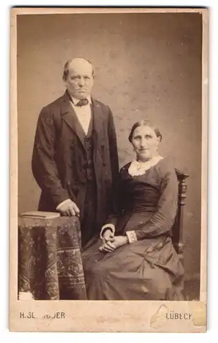 Fotografie H. Schröder, Lübeck, Beckergrube 150, Älteres Paar in zeitgenössischer Kleidung