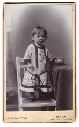 Fotografie Wilhelm Stein, Berlin, Chaussee-Str. 65-66, Kleinkind mit Ball auf Stuhl stehend