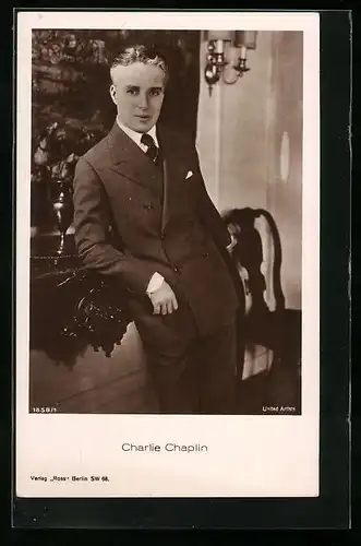 AK Schauspieler Charlie Chaplin lässig gegen einen Tisch lehnend
