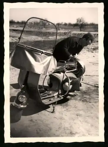 Fotografie Motorrad Vespa, Bursche bastelt am Motorroller mit Windschutzscheibe