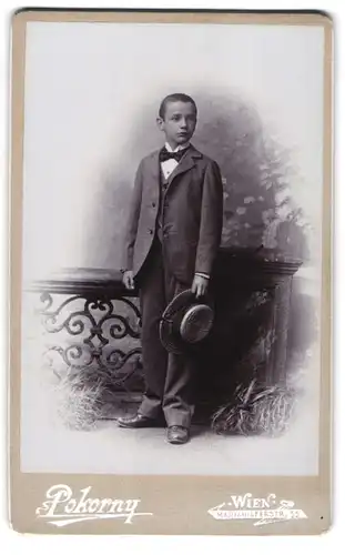 Fotografie Atelier Pokorny, Wien, Mariahilferstr. 55, Portrait frecher Bube mit Hut an einem Geländer stehend