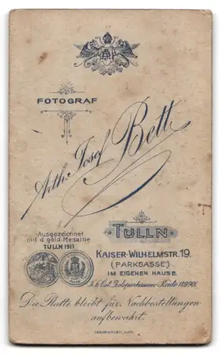 Fotografie Anth. Josef Bett, Tulln, Kaiser-Wilhelm-Str. 19, Portrait blonder frecher Bube im Mantel mit Fellkragen
