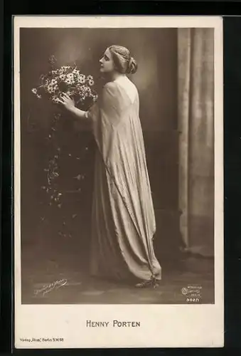 AK Schauspielerin Henny Porten, stehend in einer Robe mit einem Blumenstrauss