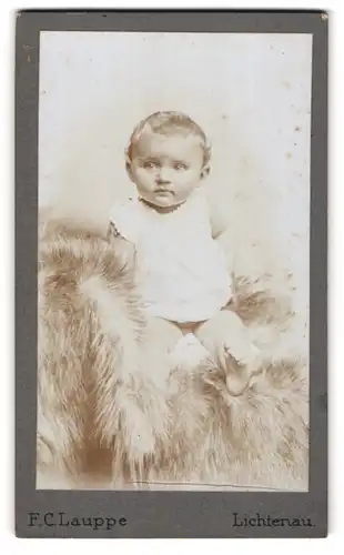 Fotografie F. C. Lauppe, Lichtenau, Halbnacktes Kleinkind im Hemd sitzt auf Fell
