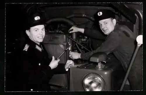 Fotografie KVP-Polizisten in Uniform schrauben am Kühler des Lastwagen's