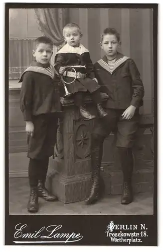 Fotografie Emil Lampe, Berlin-N., Treschkowstr. 18, Zwei halbwüchsige Knaben im Matrosenanzug und kleiner Junge mit Horn