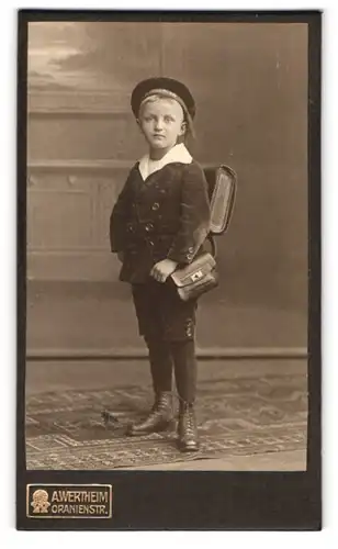 Fotografie A. Wertheim, Berlin, Oranienstr., Portrait junger Knabe im Samtanzug mit Ranzen und Mützenband Hindenburg
