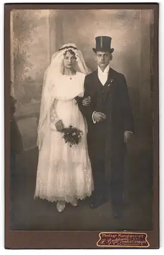 Fotografie H. Buddruss, Berlin, Steifensandstr. 5, junges Paar im Hochzeitskleid und Anzug mit Brautstrauss und Zylinder