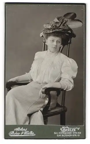 Fotografie Strom & Walter, Berlin, Köpenicker-Str. 102, junge Dame in seidener weisser Bluse mit Federhut sitzt im Stuhl