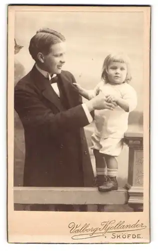 Fotografie Valborg Kjellander, Sköfde, junger Vater im Anzug mit seiner Tochter im Atelier