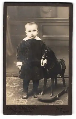 Fotografie Louis Mehlhorn, Geyer, Portrait junger Knabe im Samtkleid mit seinem Schaukelpferd im Atelier