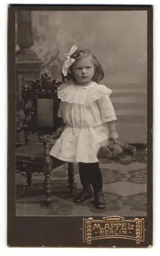 Fotografie M. Appel, Berlin, Portrait niedliches Mädchen im weissen Kleid mit Teddybär in der Hand