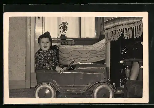 Foto-AK Kleiner Bursche in einem Spielzeugauto