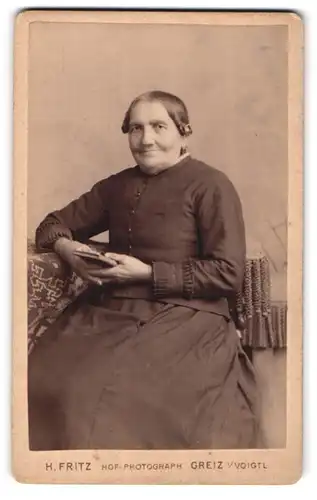 Fotografie Heinr. Fritz, Greiz, Weststr. 6, Ältere Dame in schlichter Kleidung mit Buch