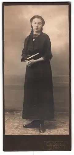 Fotografie G.E. Seige, Poessneck, Zierliche junge Frau in schwarz mit geflochtenem Haar