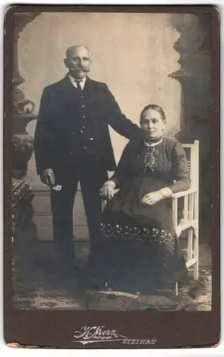 Fotografie Konrad Merz I., Steinau, Älteres Ehepaar, Mann im Anzug mit Schnauzer und hält eine Blume