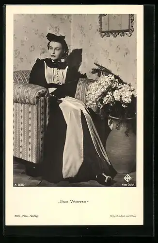 AK Schauspielerin Ilse Werner im Kostüm in Sessel sitzend mit Blumenstrauss