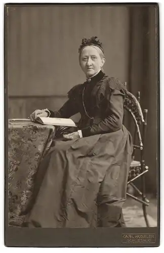 Fotografie Carl Hüseler, Schleswig, Stadtweg 34, Gestandene Frau im verzierten Kleid ein Buch lesend