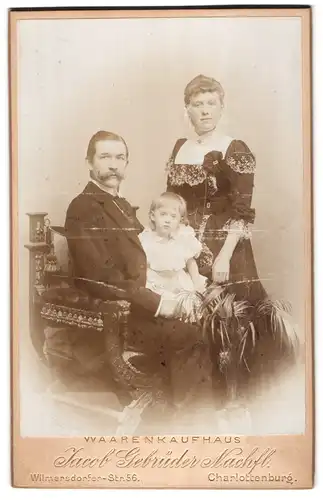 Fotografie Jacob Gebrüder Nachfl., Berlin, Stolzes Ehepaar mit kleiner Tochter auf dem Schoss des Vaters