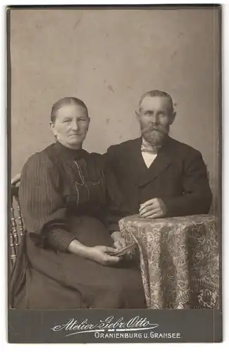 Fotografie Gebrüder Otto, Oranienburg und Gransee, Lächelndes altes Ehepaar, an einem Tisch sitzend